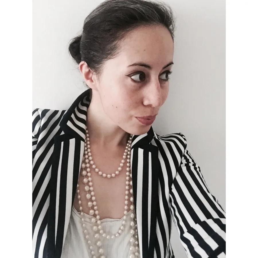 Portrait of Tessa Brooks in a black and white striped jacket and pearl necklaces